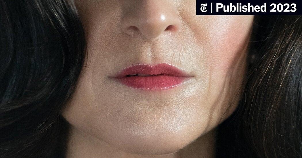 A woman in her 50s looking thoughtful, holding a small red light therapy device, symbolizing her journey to find relief during menopause. The focus is on hope and discovery.